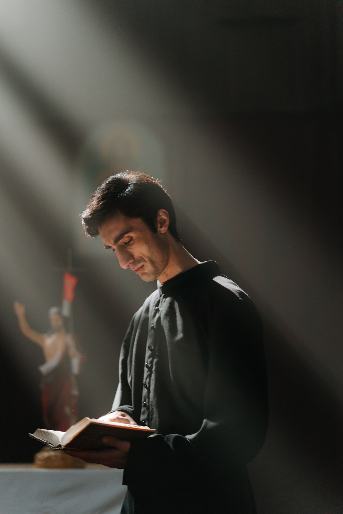 A young seminarian in a cassock in soft window light